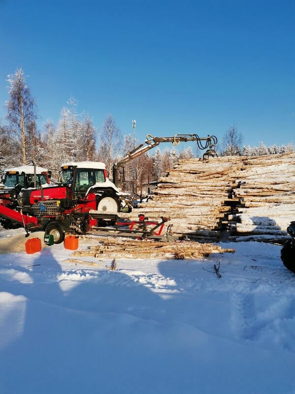 Traktori metsäkuormaimella rankapinon vieressä aurinkoisena talvipäivänä